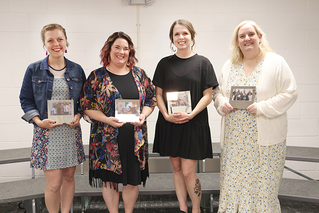 Four staff members stand with picture frame awards after winning awards