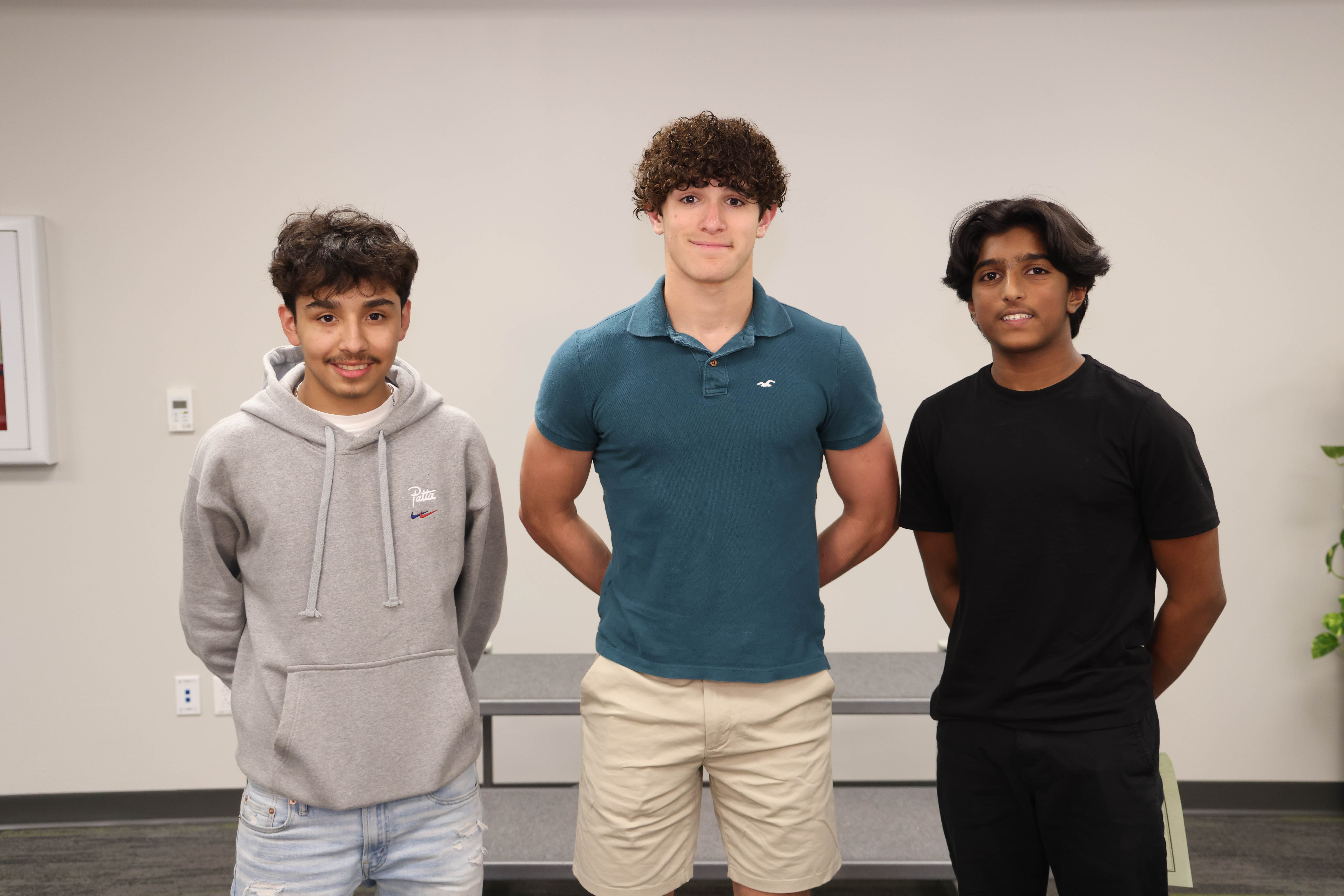 Three boys wrestling team members pose for a picture.